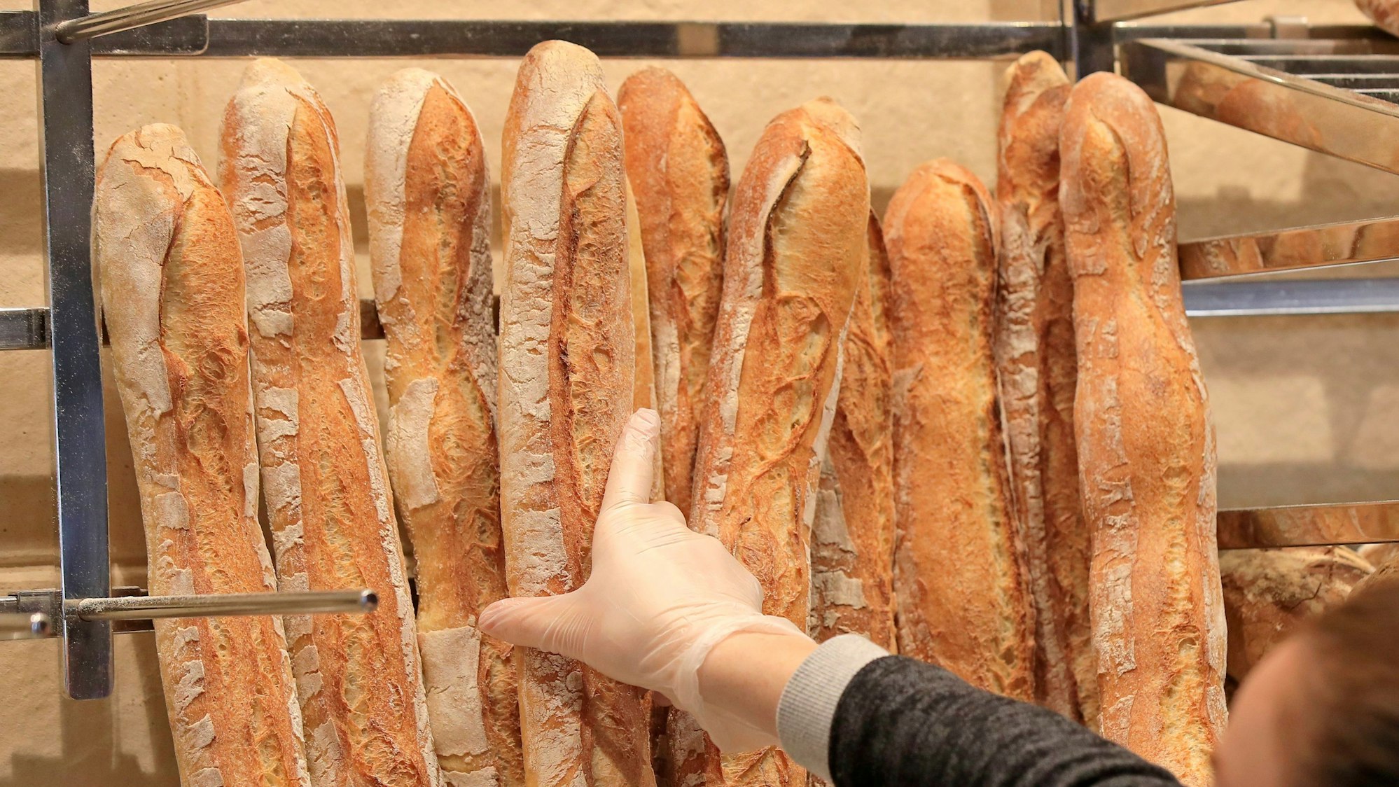 Eine Verkäuferin nimmt ein Baguette in einer Bäckerei.