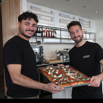 Betreiber der Caruso Focaccia Bar halten ein Blech mit Focaccia in die Kamera