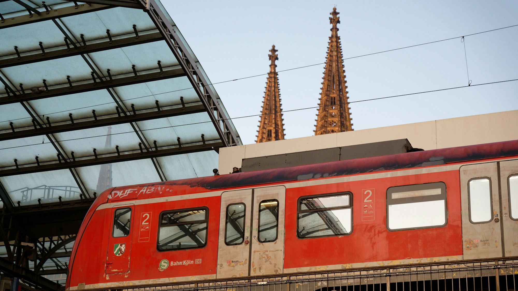 Eine S-Bahn steht im Hauptbahnhof in Köln. Im Hintergrund sind die Domspitzen zu sehen.