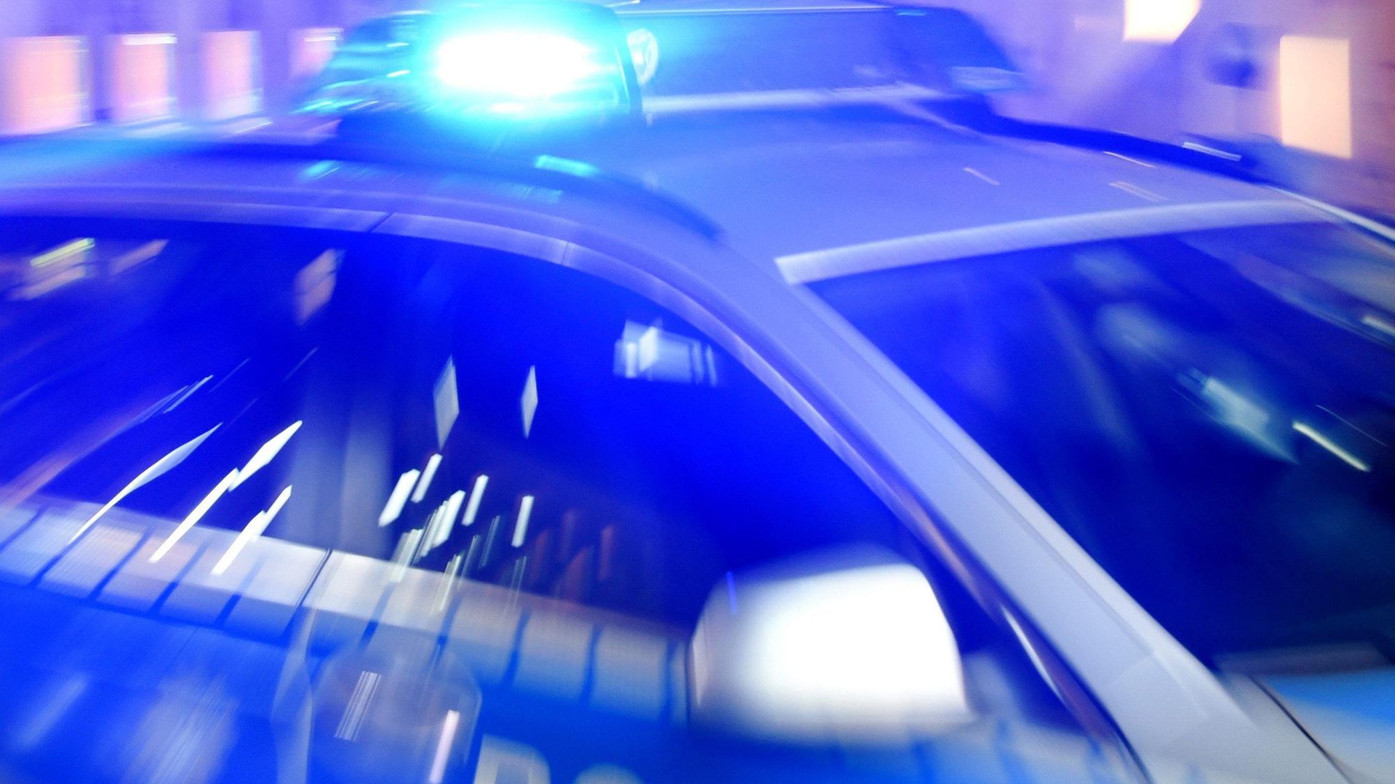 Ein Streifenwagen der Polizei steht mit eingeschaltetem Blaulicht auf der Straße.