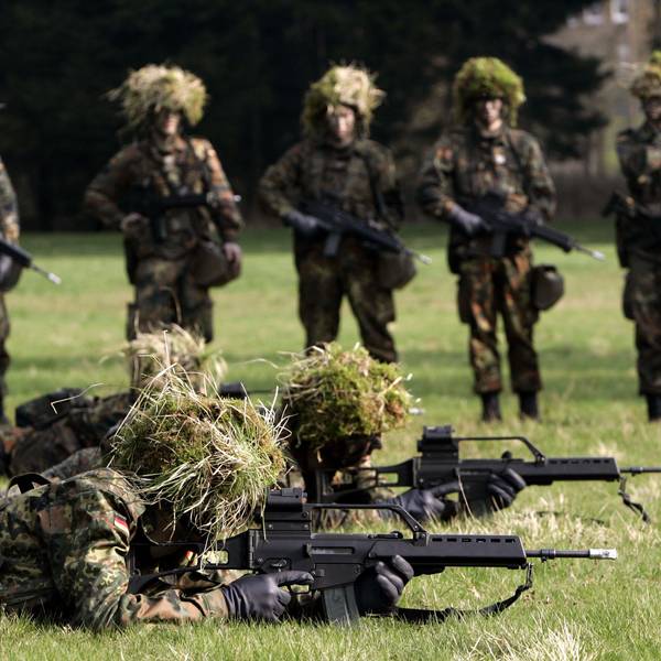 Hessen, Schwarzenborn: Mit Blattwerk und Gras getarnte Wehrpflichtige von den Panzergrenadieren liegen mit Gewehren des Typs G36 auf dem Bauch in Deckung, im Hintergrund werden sie von ihren Kameraden beobachtet. (Archivbild)