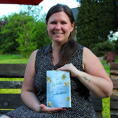 Eine junge Frau hält ein Buch in die Kamera.