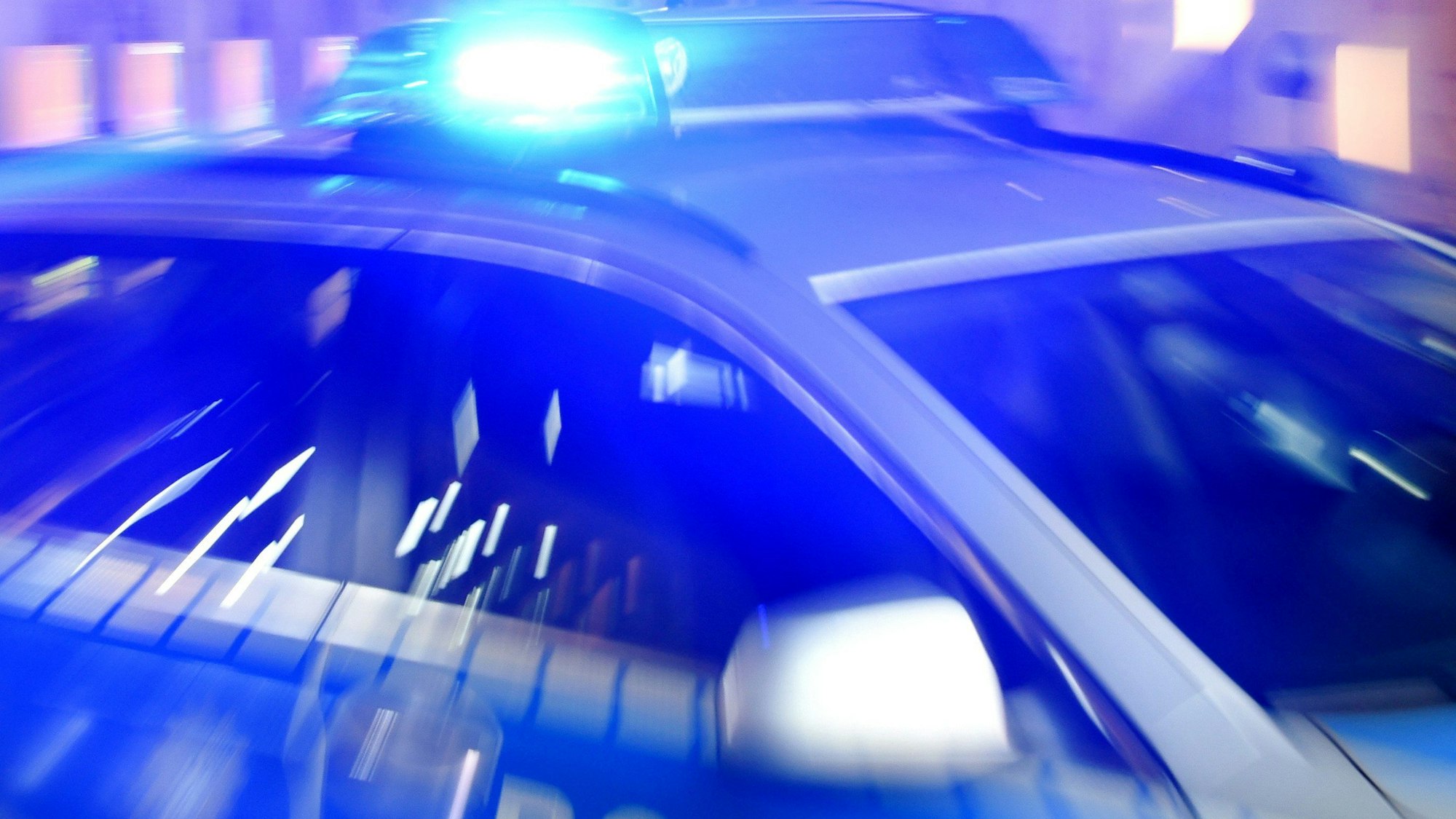 Ein Streifenwagen der Polizei steht mit eingeschaltetem Blaulicht auf der Straße.