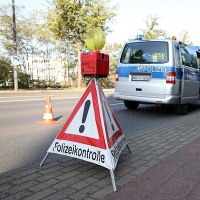Ein dreieckiges Warnschild weist am Straßenrand auf eine Polizeikontrolle hin
