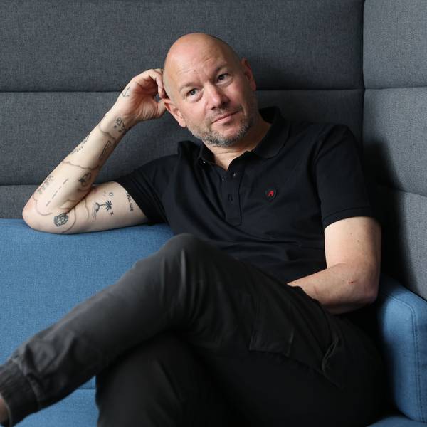 Porträtfoto von Mike Heßler, der auf einem Sofa sitzt.