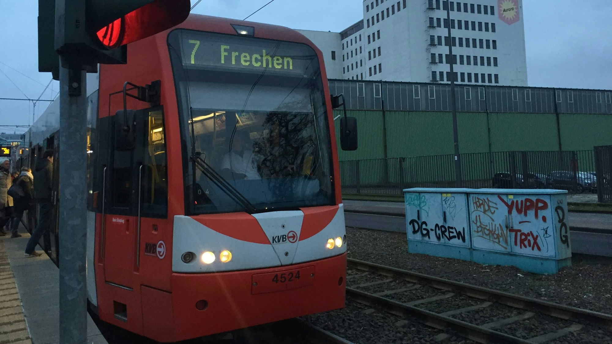 Auf dem Foto ist eine rote Bahn der KVB zu sehen, die an einer Station hält.