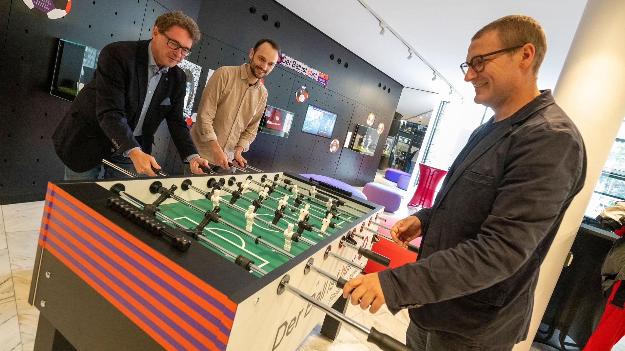 Drei Männer spielen Tischkicker.