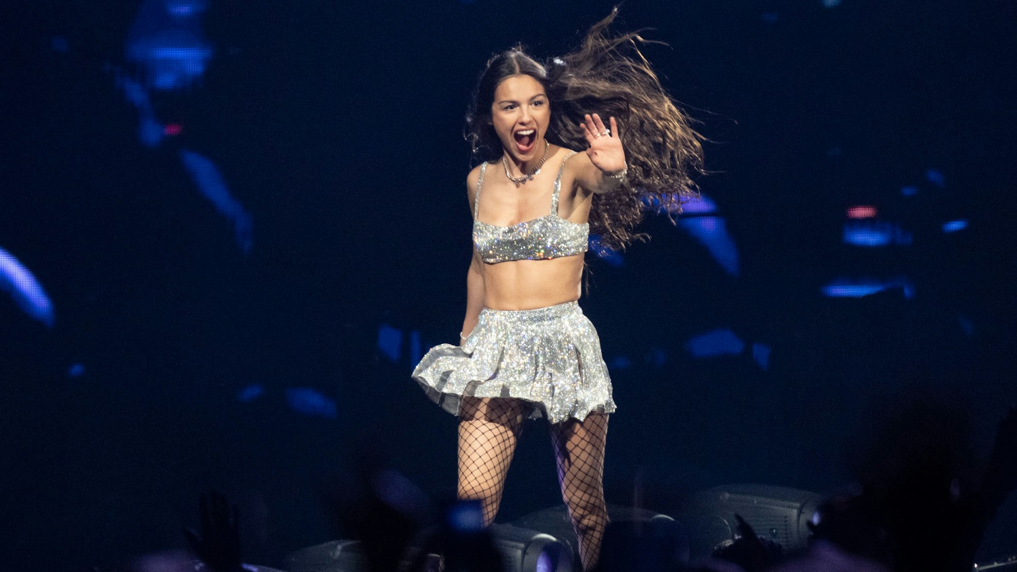 12.06.2024, Köln: Die amerikanische Schauspielerin und Sängerin Olivia Rodrigo tritt in der Lanxess Arena auf. Sie trägt ein silbernes Top und einen silbernen Falten-Minirock und grüßt ihre Fans.