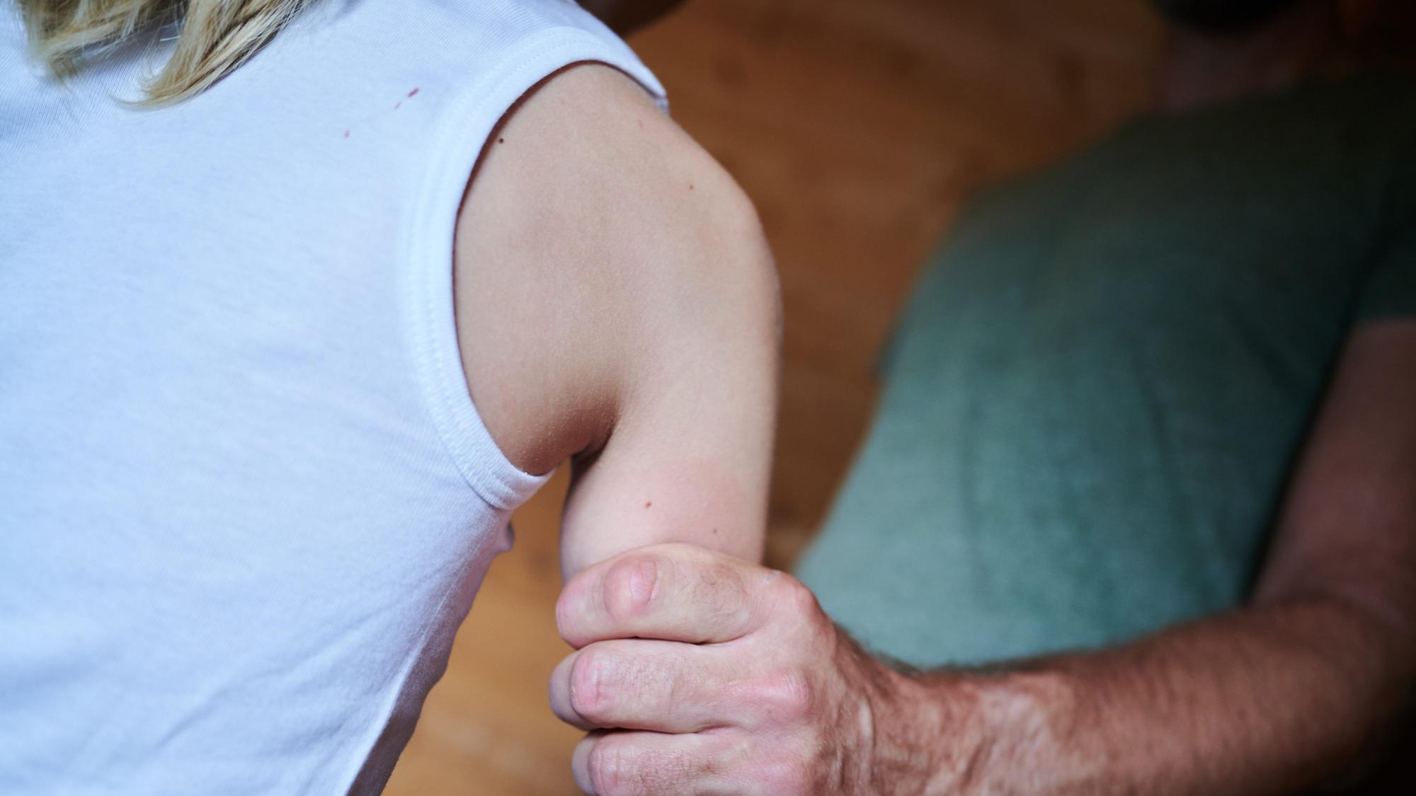 Ein Mann hält ein Kind fest am Arm (gestellte Szene).