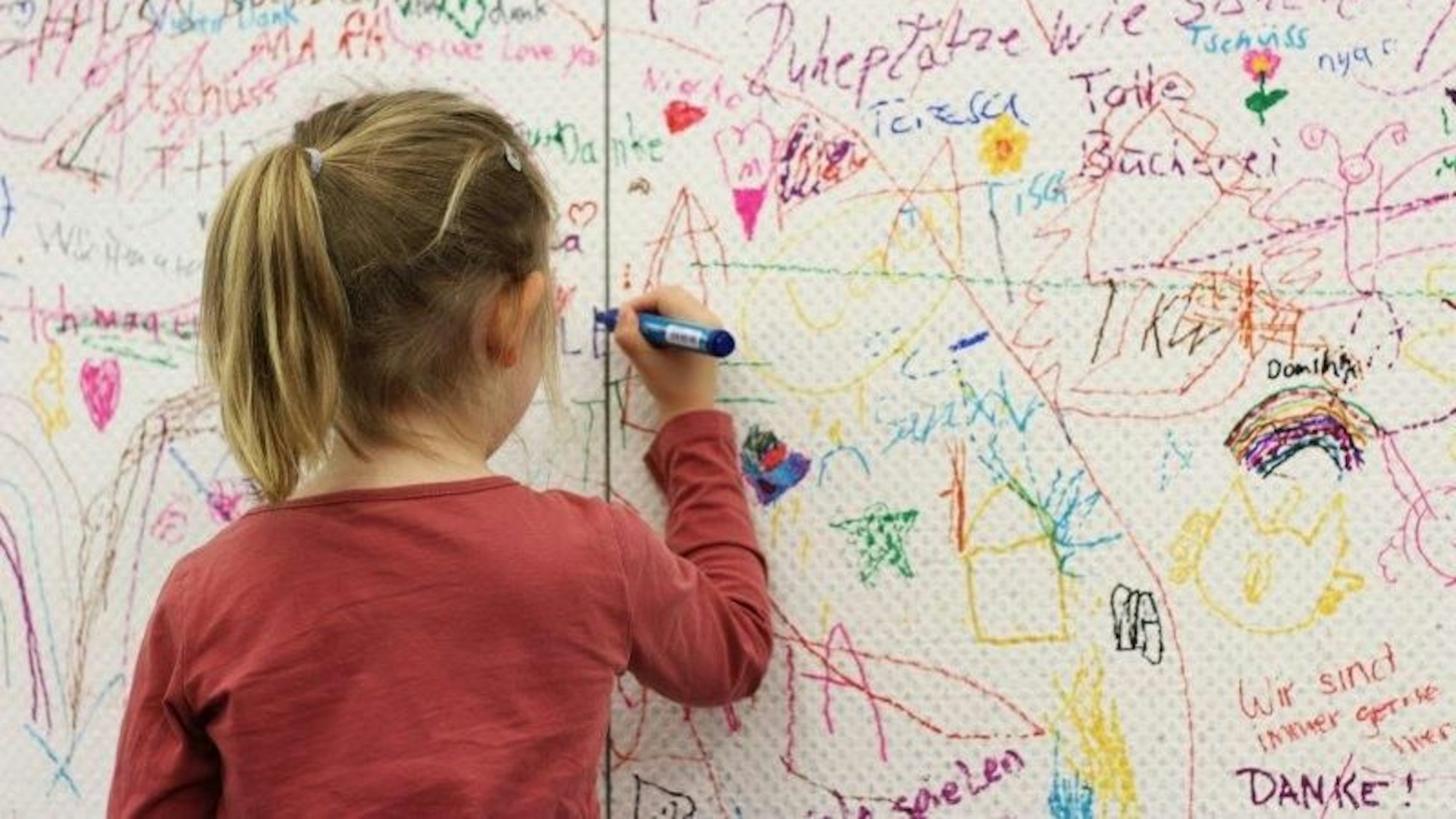 Ein Kind zeichnet an der Abschiedswand in der Stadtbibliothek.