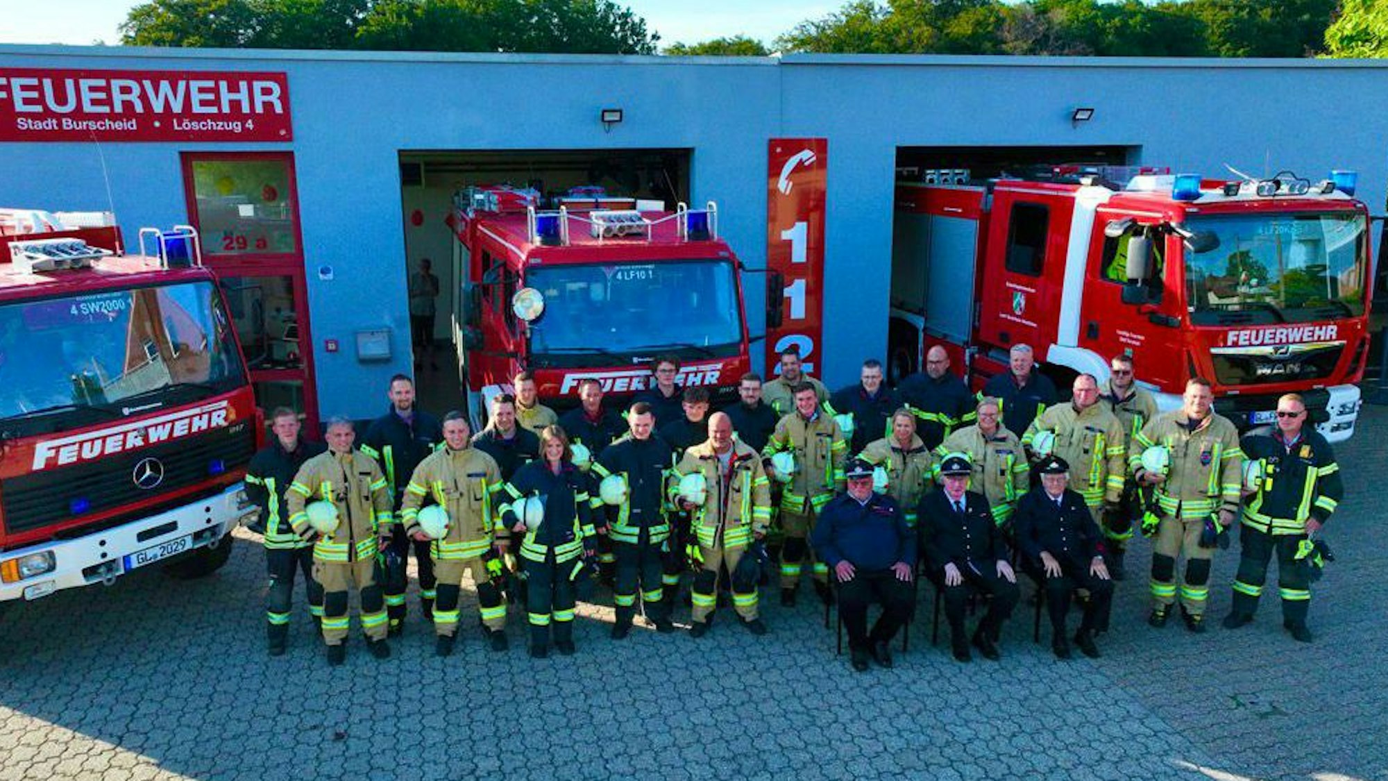 Feuerwehrmänner stehen vor Einsatzfahrzeugen.