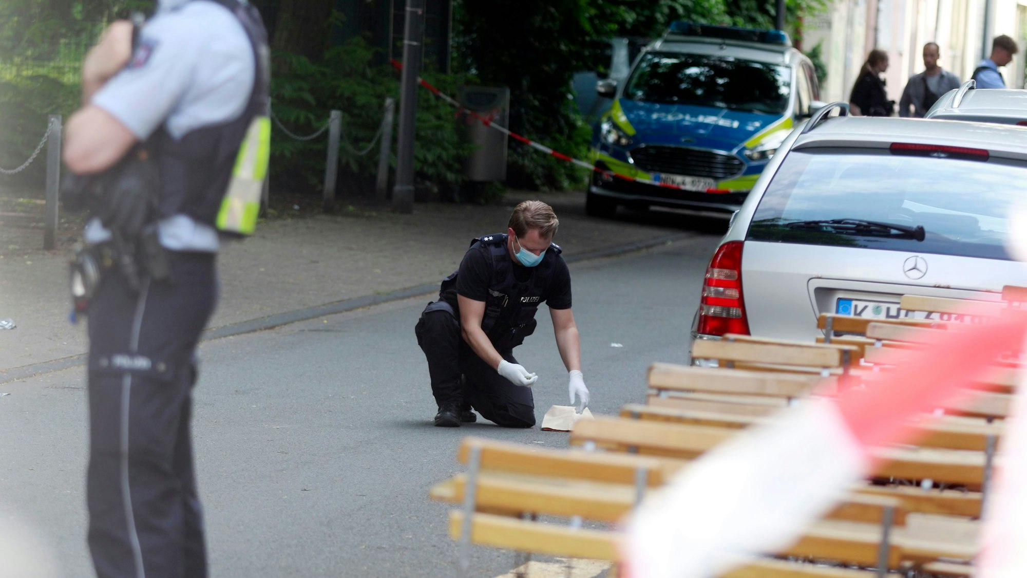 Ein Polizist sichert Spuren an einem abgesperrten Tatort.