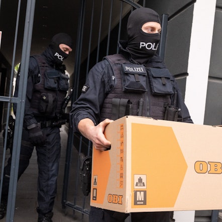 Ein Polizist trägt im April 2024 bei der Razzia zum sogenannten „Edelschleuser-Skandal“ beschlagnahmte Unterlagen aus einem Gebäude in Bonn.