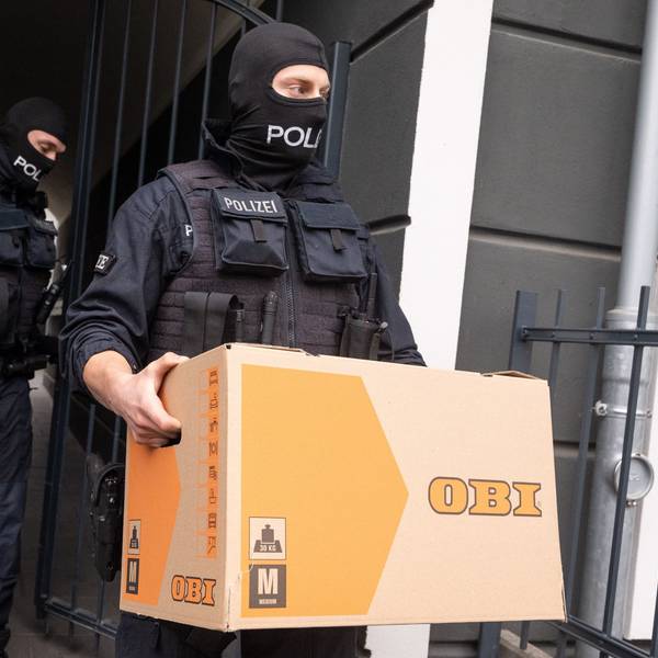 Ein Polizist trägt bei der Razzia gegen die mutmaßliche Schleuserbande im April 2024 einen Karton aus einem Gebäude.