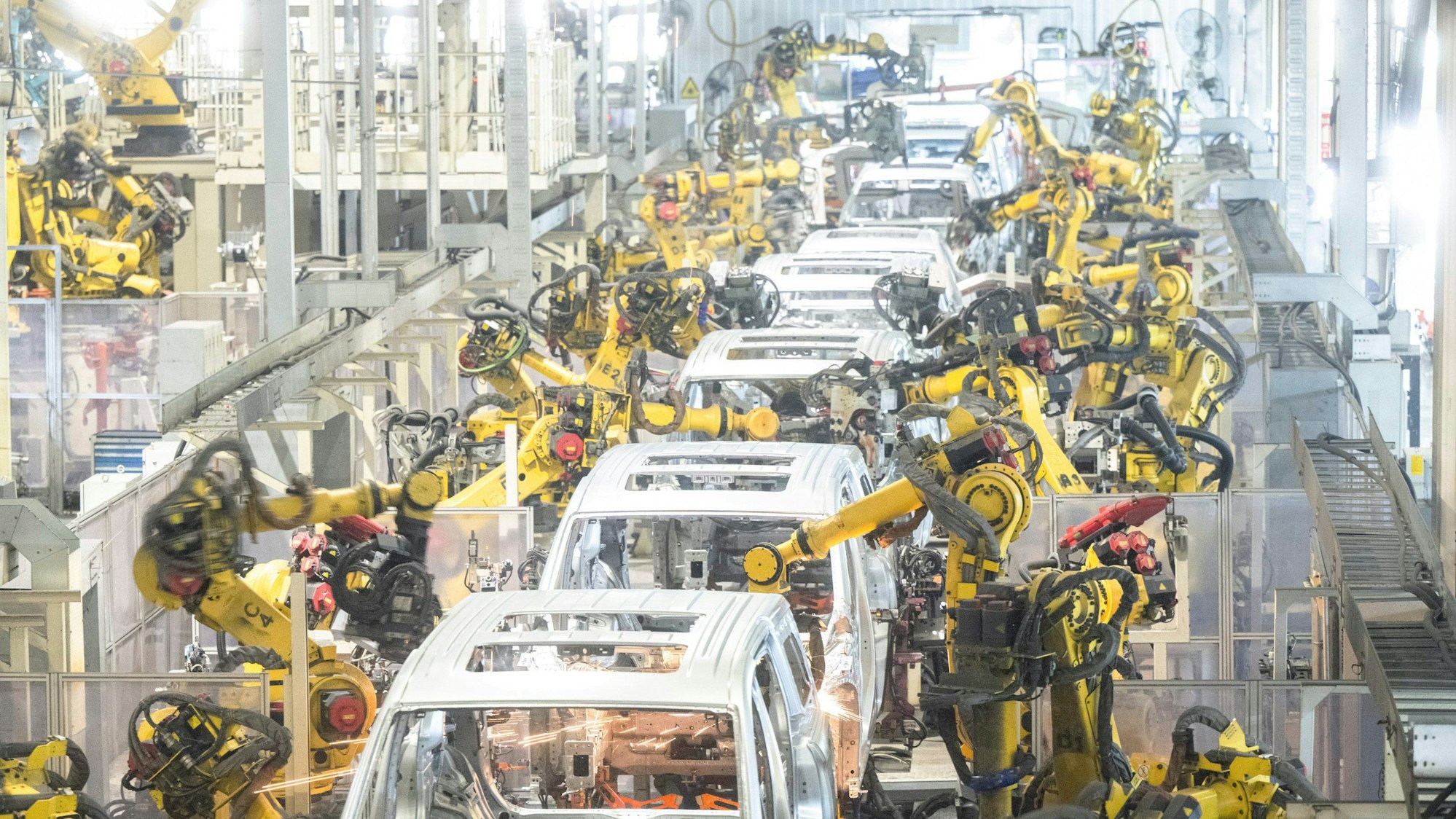 ARCHIV - 01.04.2024, China, Wuhan: Roboter arbeiten in einer Schweißwerkstatt von Voyah, einer chinesischen Elektroautomarke, in Wuhan in der zentralchinesischen Provinz Hubei. (zu dpa: «EU-Kommission droht hohe Strafzölle auf E-Autos aus China an») Foto: Xiao Yijiu/XinHua/dpa +++ dpa-Bildfunk +++