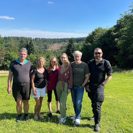 Drei Männer und drei Frauen stehen auf einer Wiese.