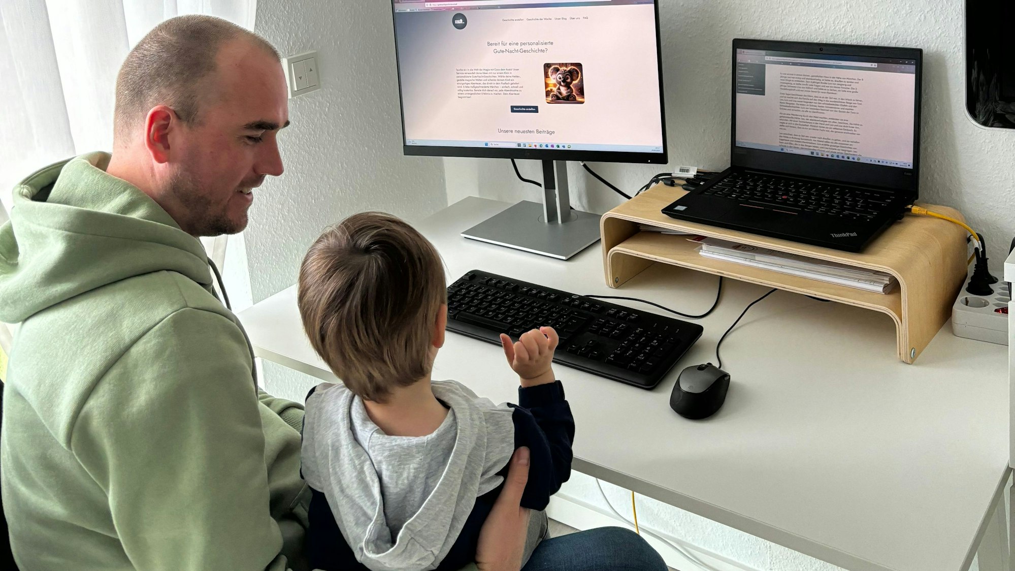 Vater und Sohn sitzen vor dem Computer, auf dem eine Gute-Nacht-Geschichte zu lesen ist.