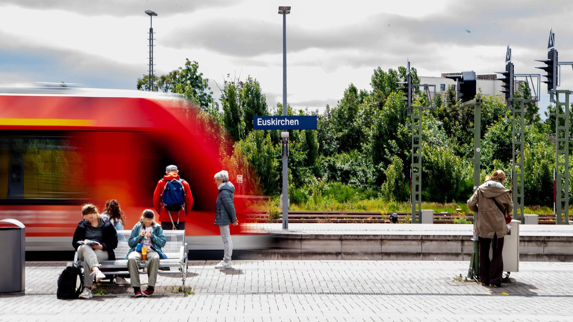 Mehrere Personen warten auf einem Bahnsteig in Euskirchen auf den einfahrenden Zug.