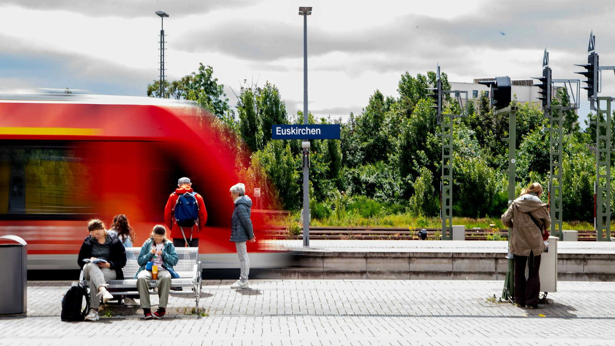 Mehrere Personen warten auf einem Bahnsteig in Euskirchen auf den einfahrenden Zug.