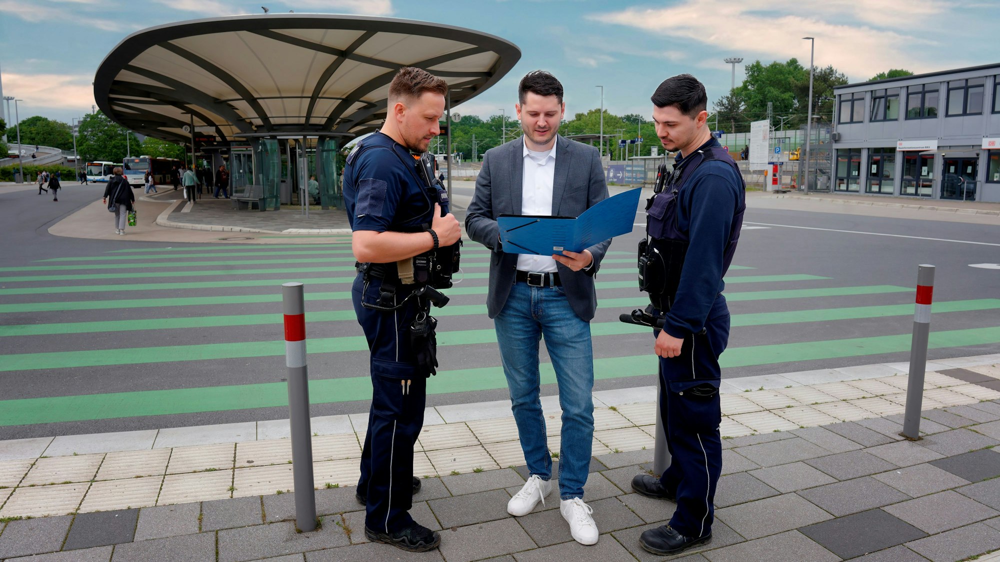 Drei Männer blicken in eine aufgeschlagene Mappe.