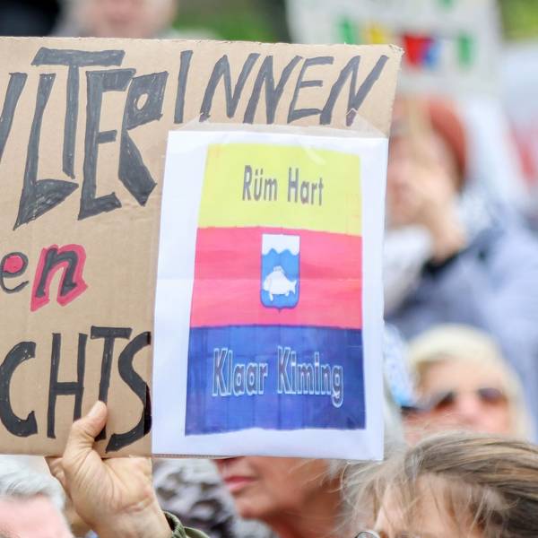 Teilnehmer halten bei einer Kundgebung Pappschilder hoch, darunter ein Schild mit dem Schriftzug „SylterInnen gegen Rechts“.