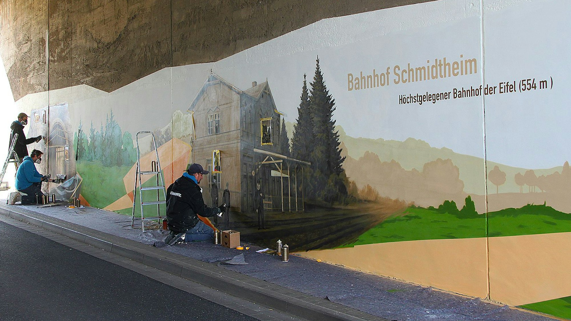 Zu sehen sind drei Künstler bei der Arbeit in der Unterführung.
