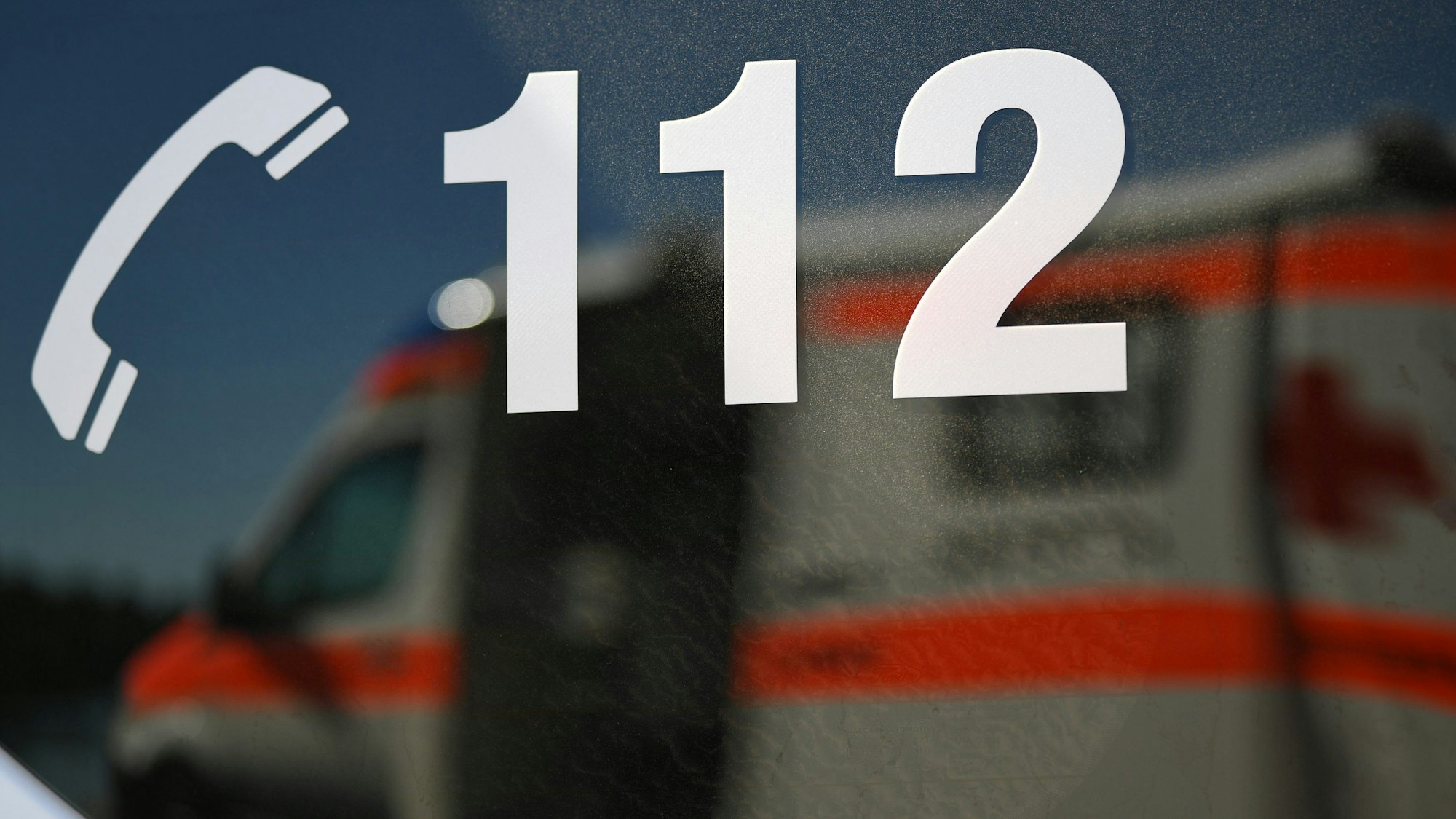 Ein Rettungswagen spiegelt sich während einer Übung in einem Fenster eines anderen Rettungswagen mit der Aufschrift „112“.