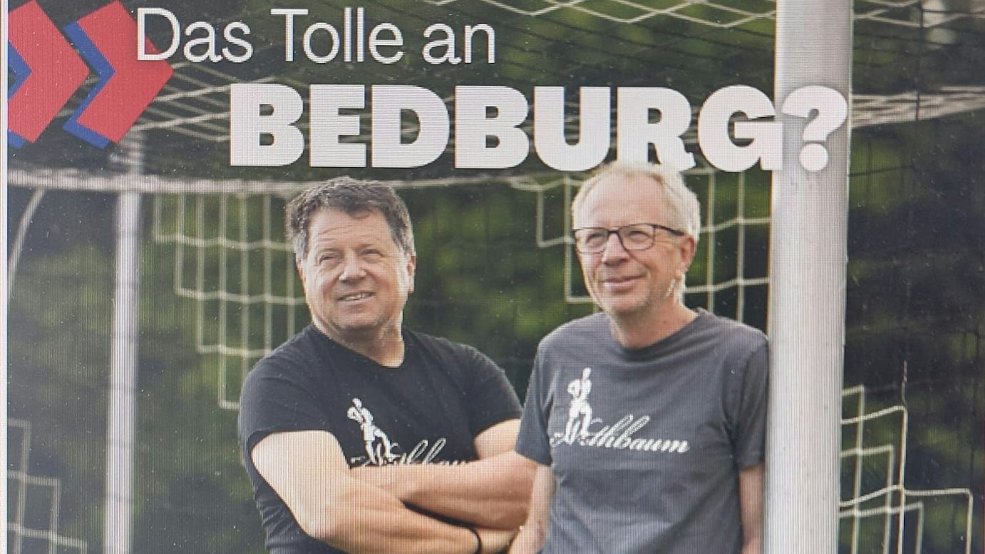 Zwei Männer stehen an einem Torpfosten.