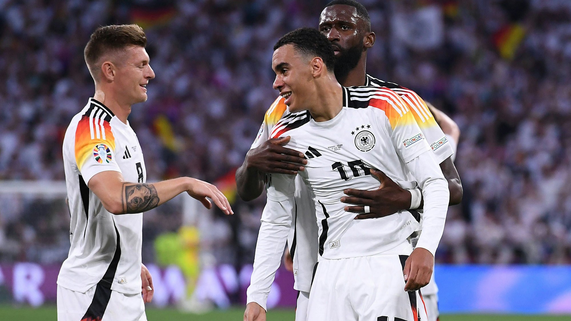 Torschütze Jamal Musiala wird von Toni Kroos (l.) und Antonio Rüdiger (hinten) nach seinem Treffer zum 2:0 gefeiert.