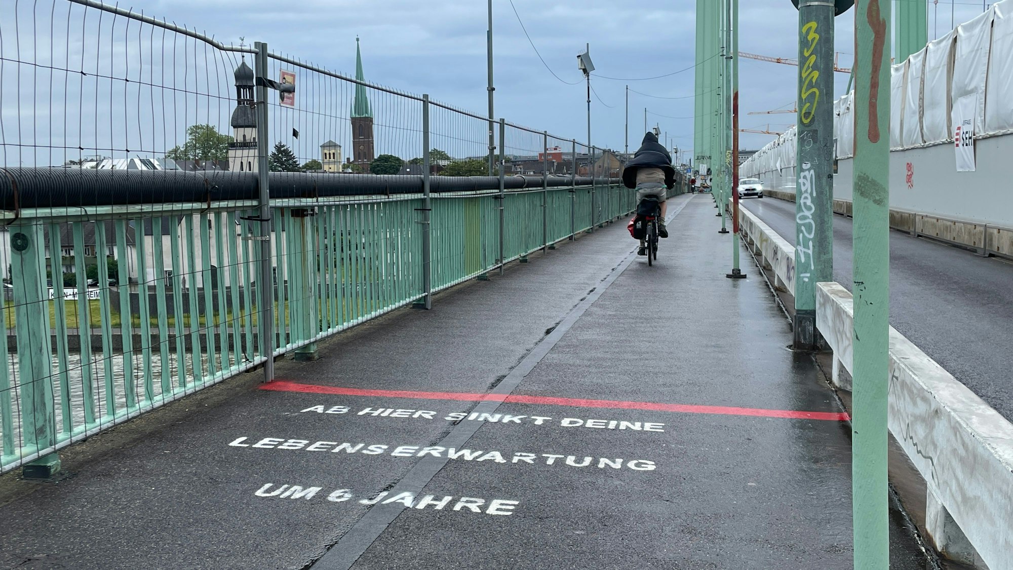 “Ab hier sinkt deine Lebenserwartung um 6 Jahre”: Dieser in Richtung der rechtsrheinischen Stadthälfte ausgerichtete Schriftzug ist seit Montag, dem 3. Juni auf Kölner Brücken zu sehen. Eine Analyse zeigt nun aber, dass die These nicht stimmt.
