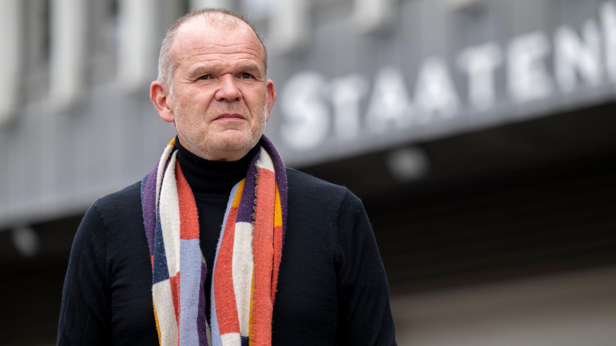 Francois-Xavier Roth steht vor dem Staatenhaus. Er trägt einen dunklen Pullover und darüber einen gemusterten Schal