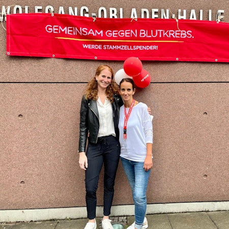 Zwei Frauen unter einem Banner der DKMS.