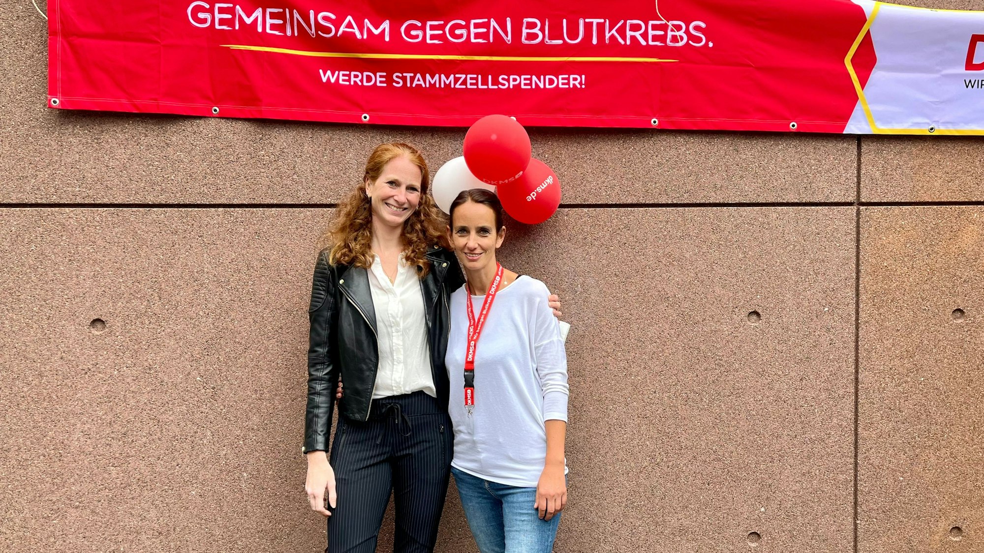 Zwei Frauen unter einem Banner der DKMS.