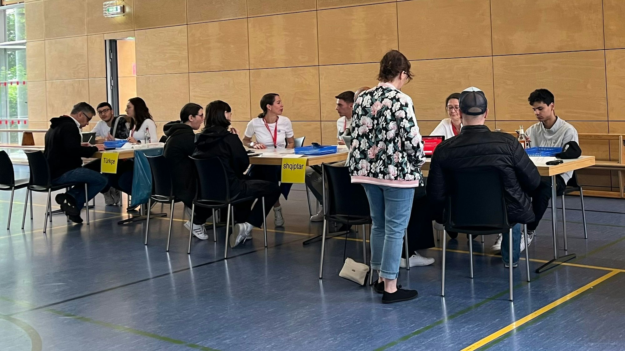 Tische mit Menschen in einer Turnhalle