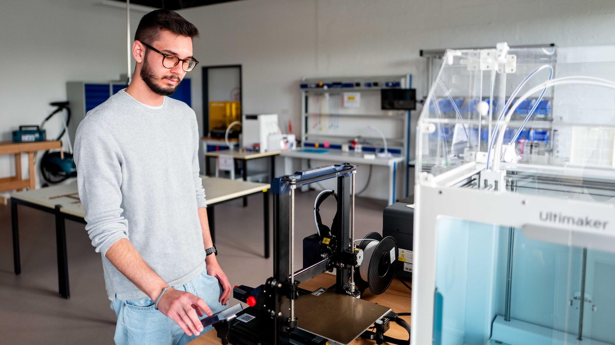 Ein Mann bedient den 3D-Drucker.