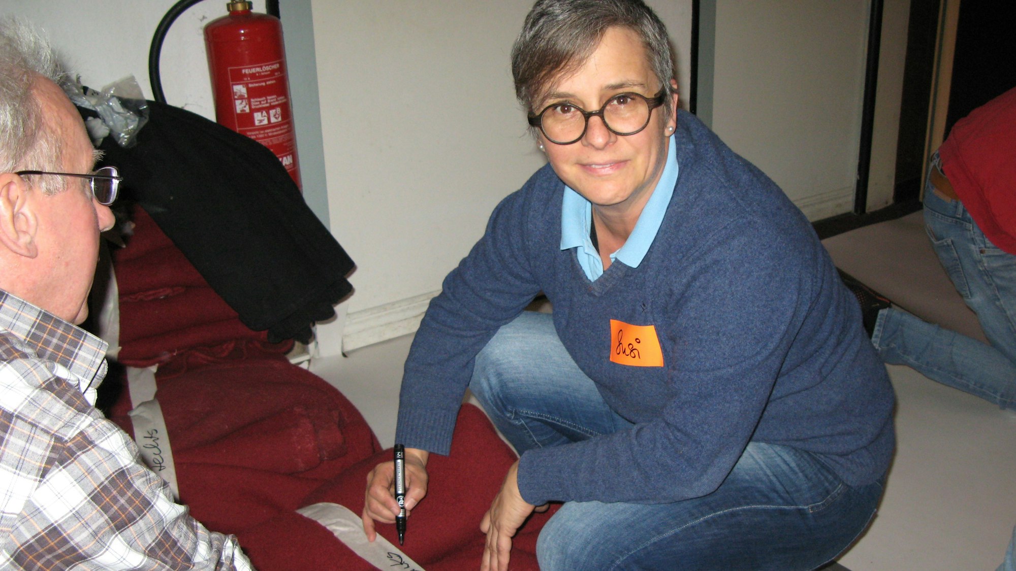 Susanne Dittrich beschriftet auf Kreppband einen abgehängten roten Vorhang.