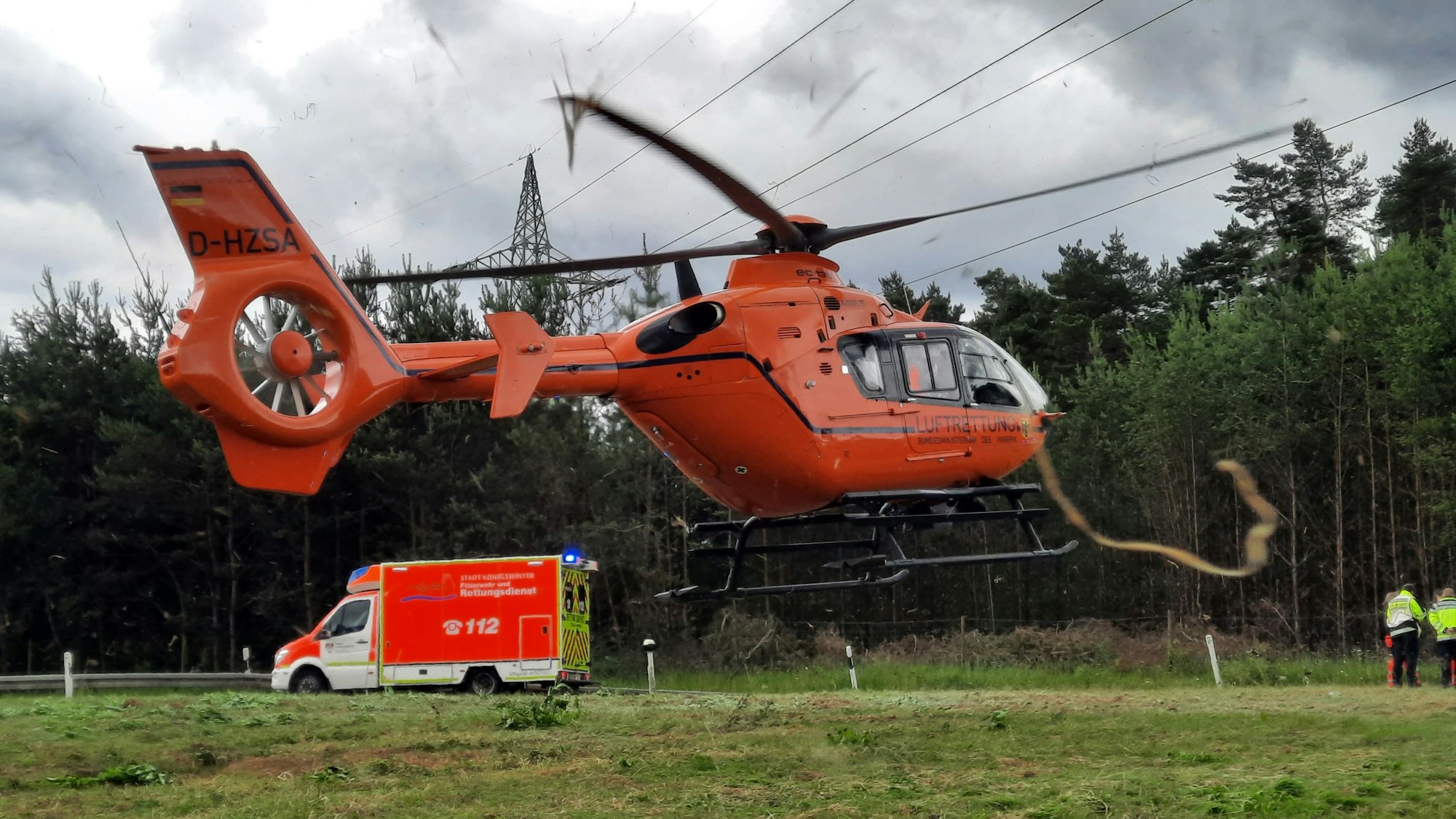 Ein Rettungshubschrauber beim Start, im Hintergrund steht ein Rettungswagen.