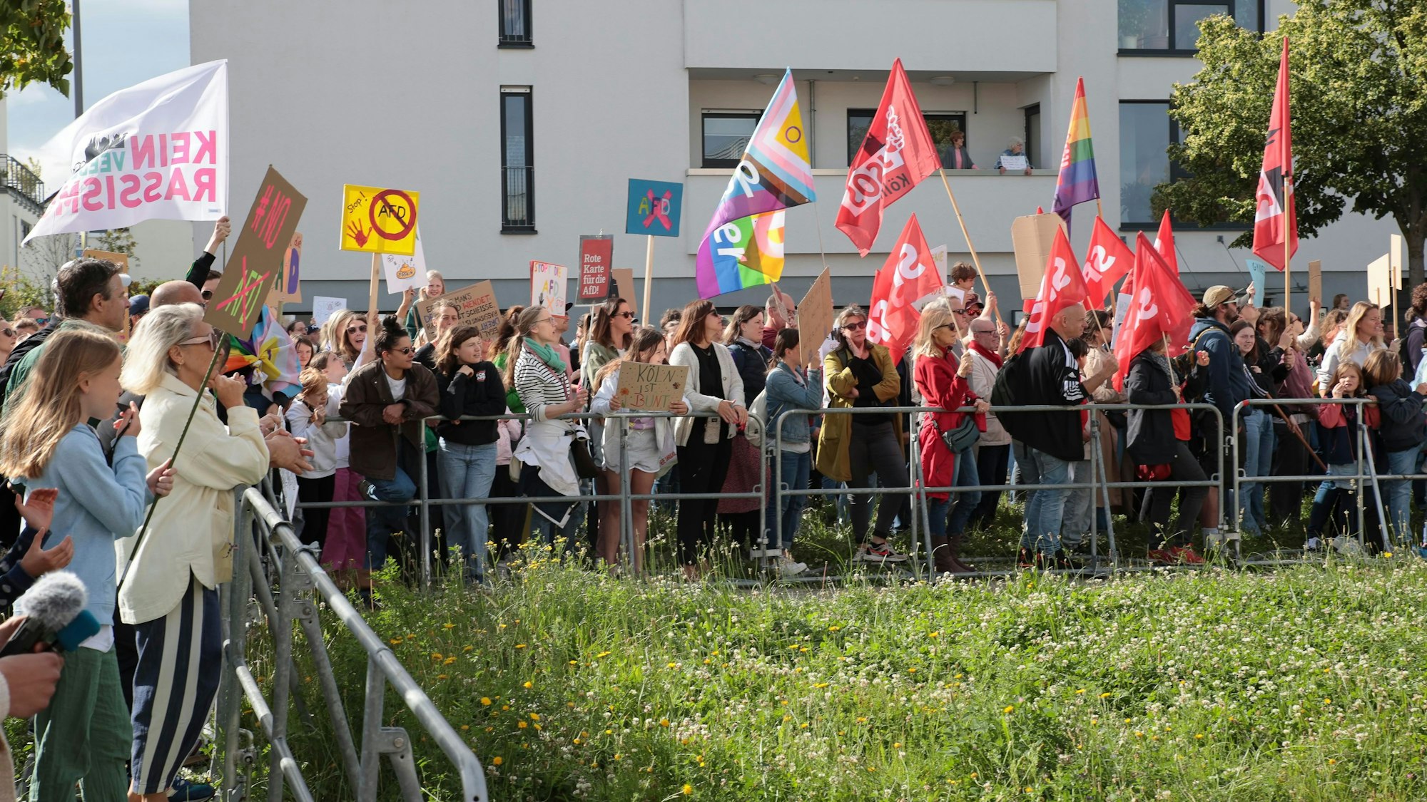 Menschen in Köln-Widdersdorf protestieren mit Fahnen und Plakaten gegen die AfD.