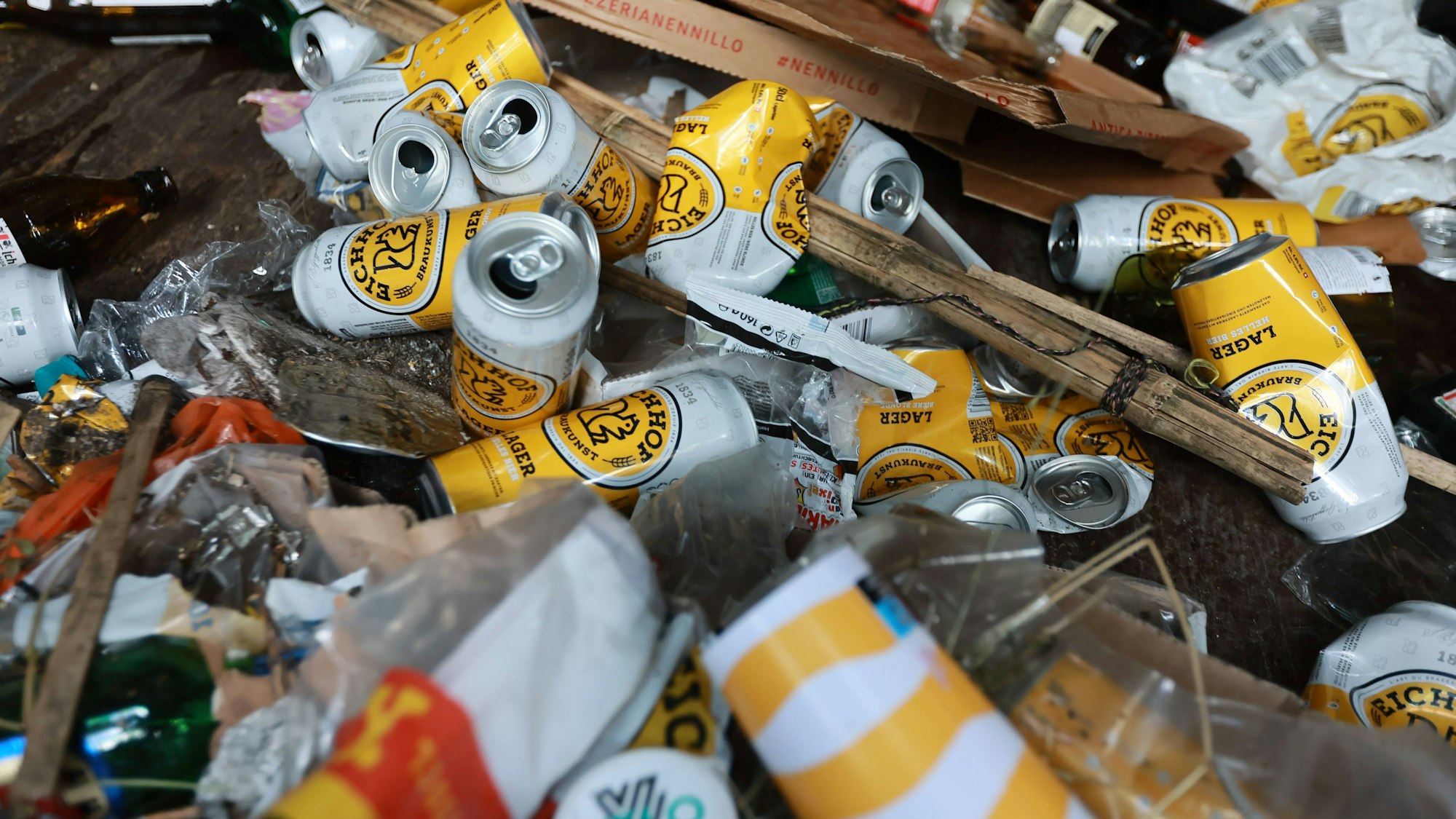 Ein Haufen leerer Bierdosen, Pizzakartons und Plastikmüll liegt auf einem Haufen.