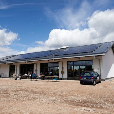 Der Neubau des Dorfgemeinschaftshauses Glehn hat PV-Anlagen auf dem Dach. Davor stehen Bierbänke für die Einweihungsfeier.