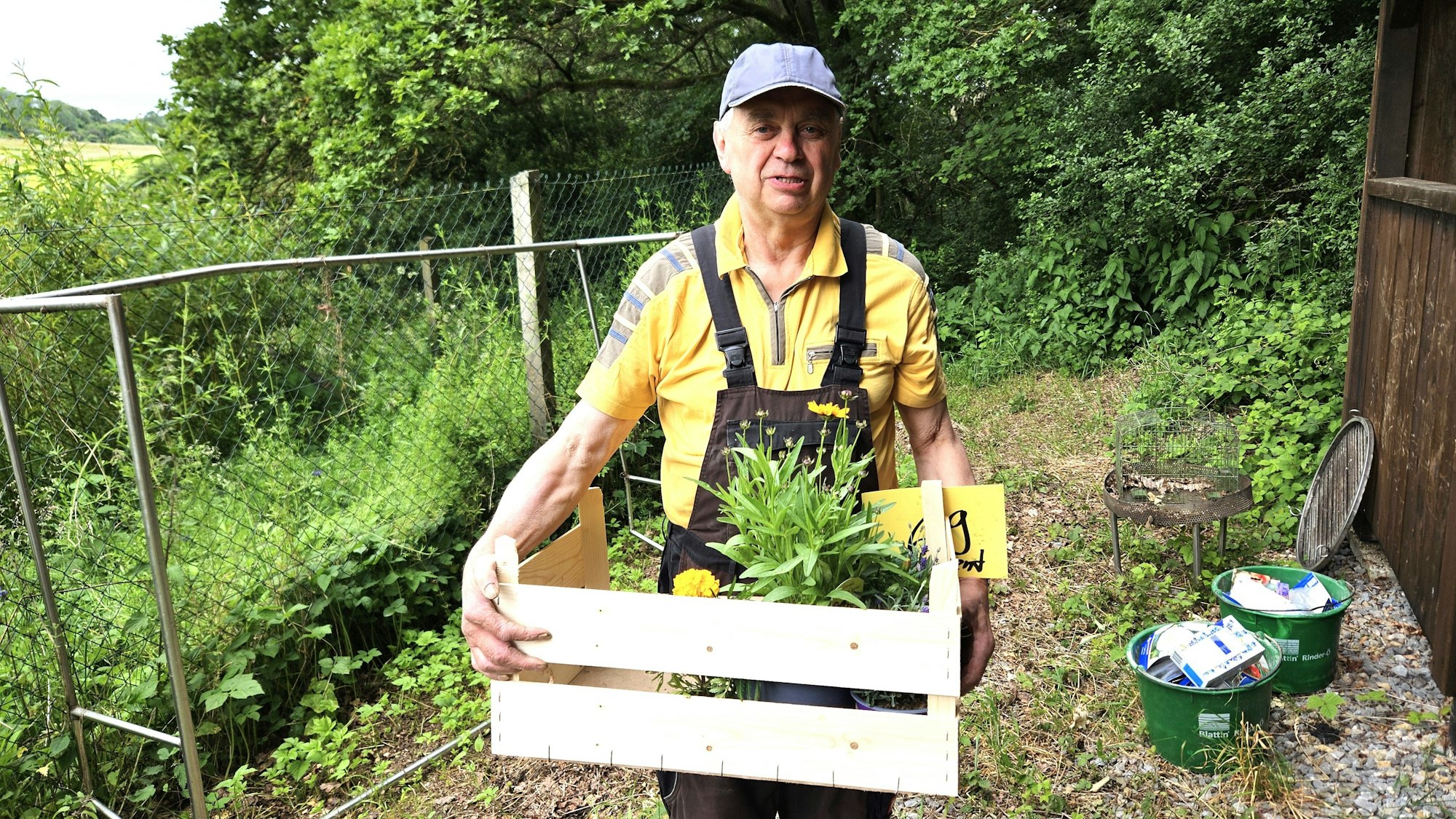 Rudi Diefenbach hält eine Holzkiste mit Blumen.