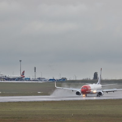 Eine Boeing 737 der norwegischen Fluggesellschaft Norwegian landet während eines Gewitters auf einer Landebahn. Regen spritzt von der Landebahn nach oben. (Archivbild)