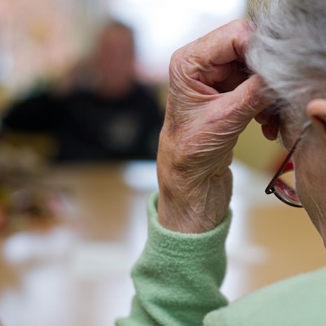 Eine demenzkranke Frau sitzt in einem Pflegeheim. Nachlassende kognitive Fähigkeiten führen bei viele Senioren zu Frustrationen.