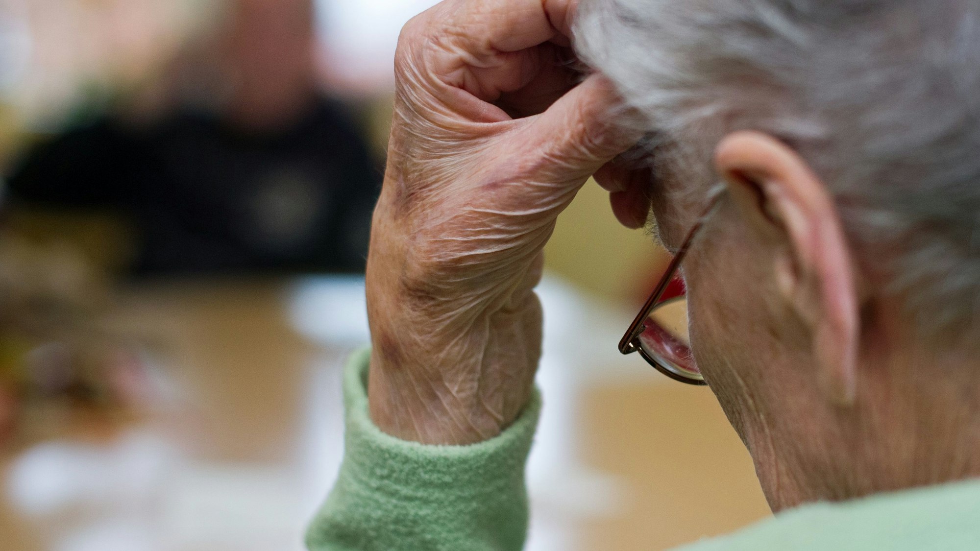 Eine demenzkranke Frau sitzt in einem Pflegeheim. Nachlassende kognitive Fähigkeiten führen bei viele Senioren zu Frustrationen.