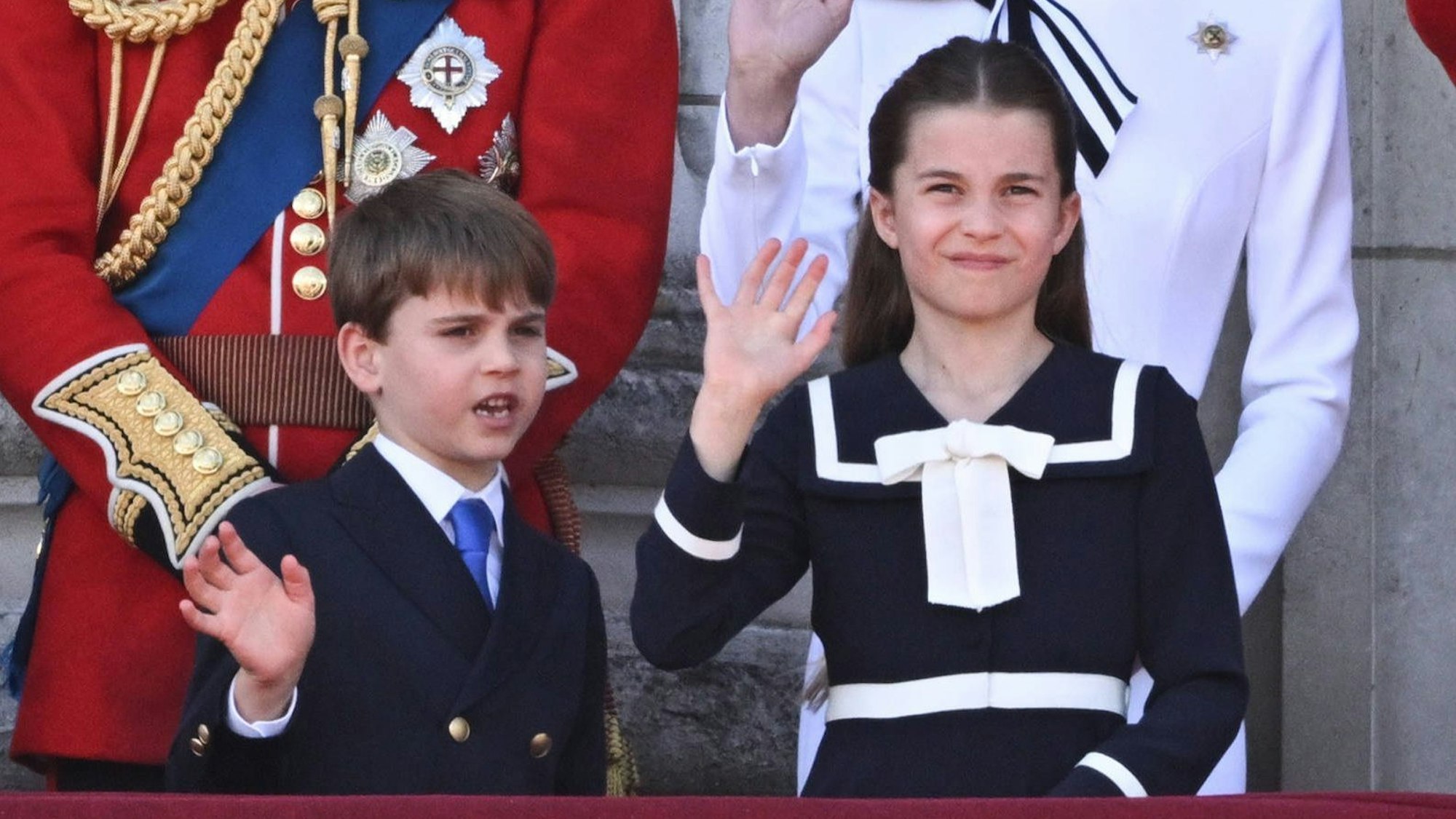 Prinz Louis spricht mit seiner Schwester Prinzessin Charlotte während beide winken.