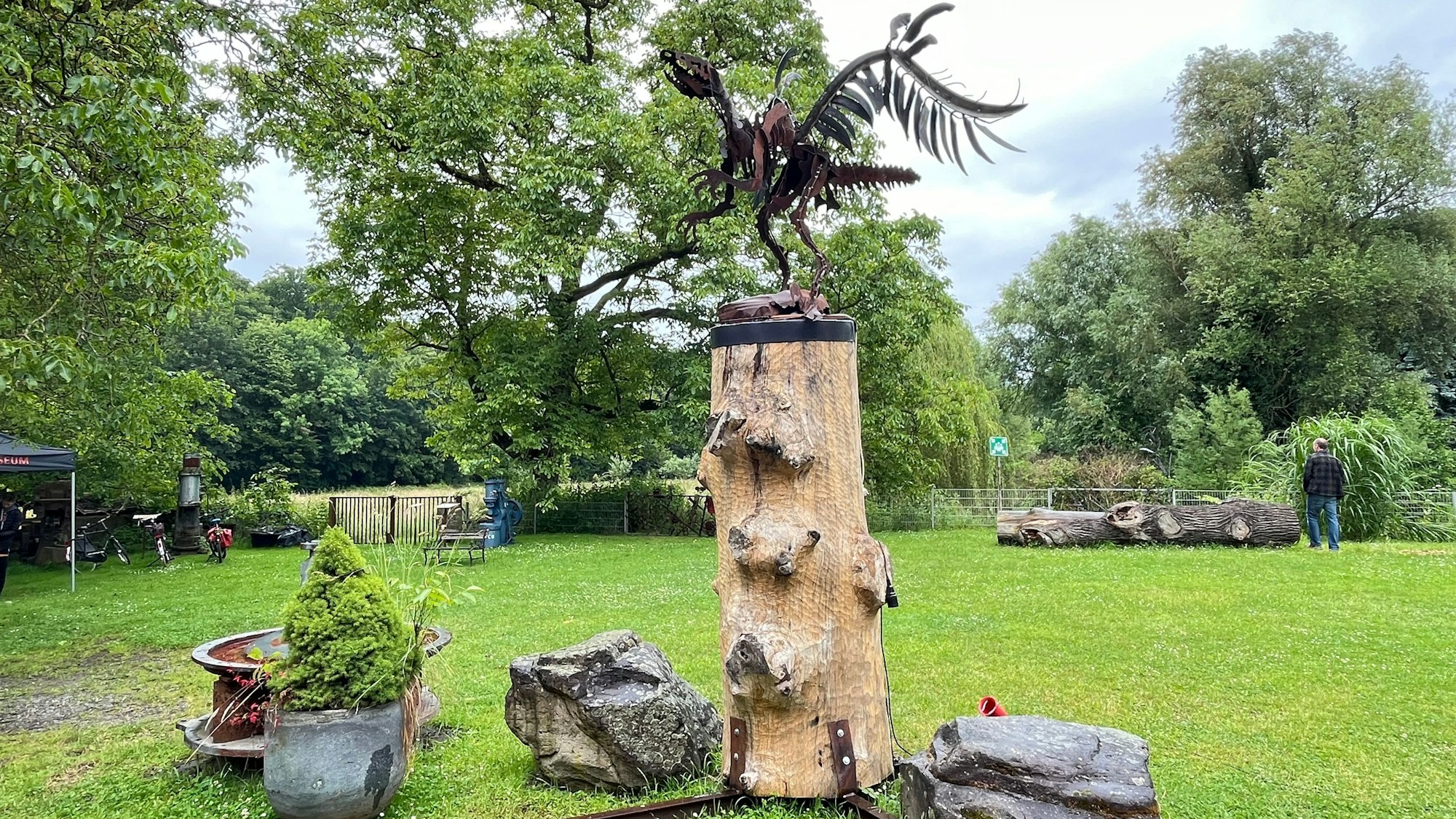 Metall-Saurier auf Baumstamm.