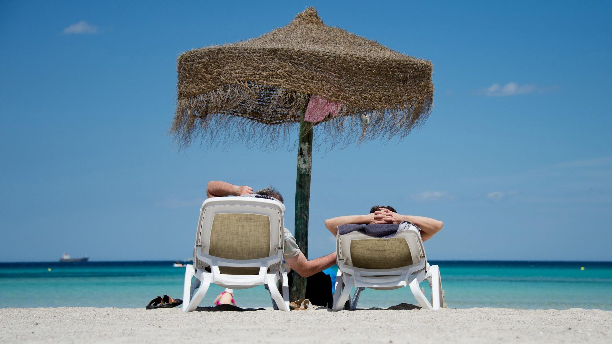 Urlauber liegen am Strand an der Plaja de Muro im Norden der Mittelmeerinsel Mallorca.