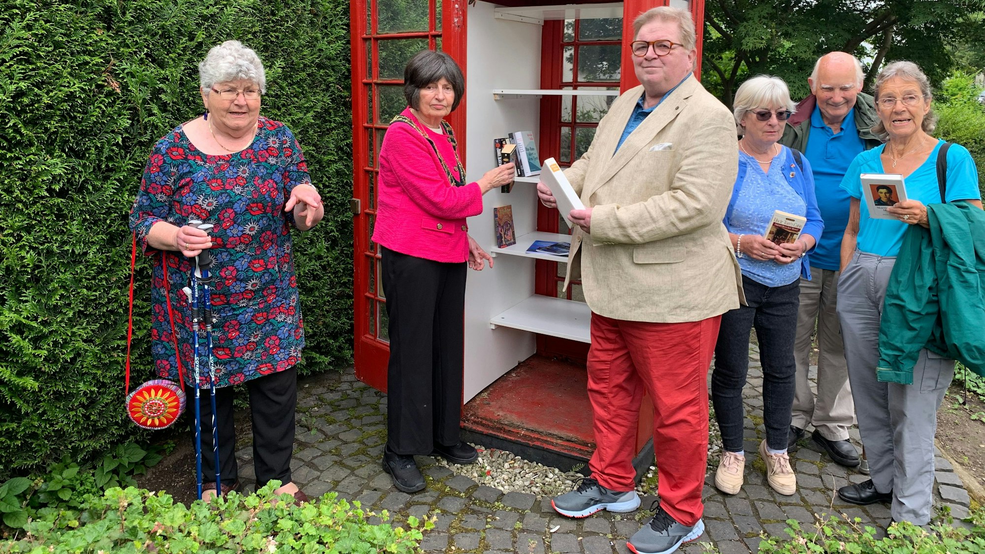 Mehrere Menschen stehen an einem öffentlichen Bücherschrank.