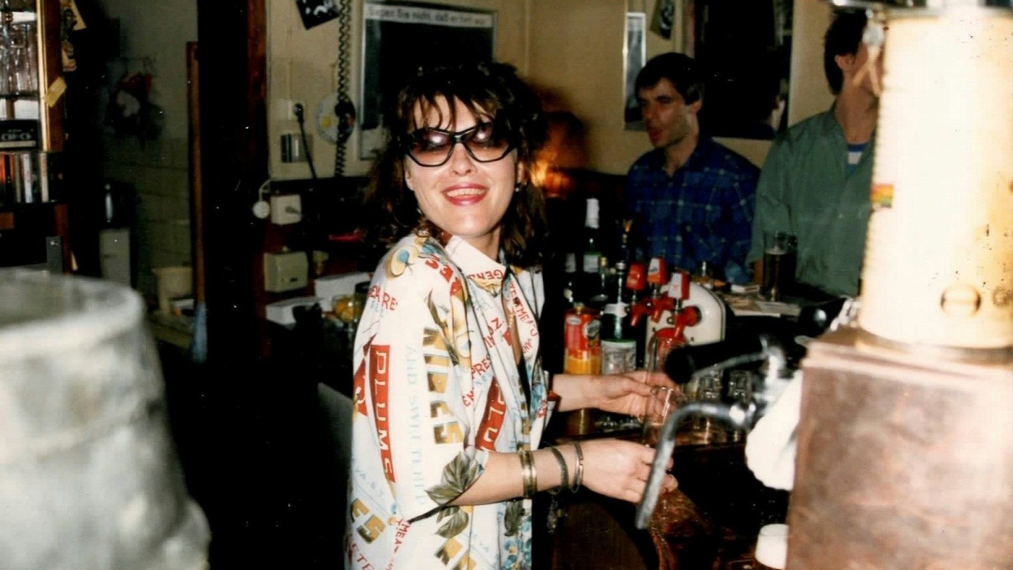 Eine Frau mit Sonnenbrille hinter einer Kneipentheke