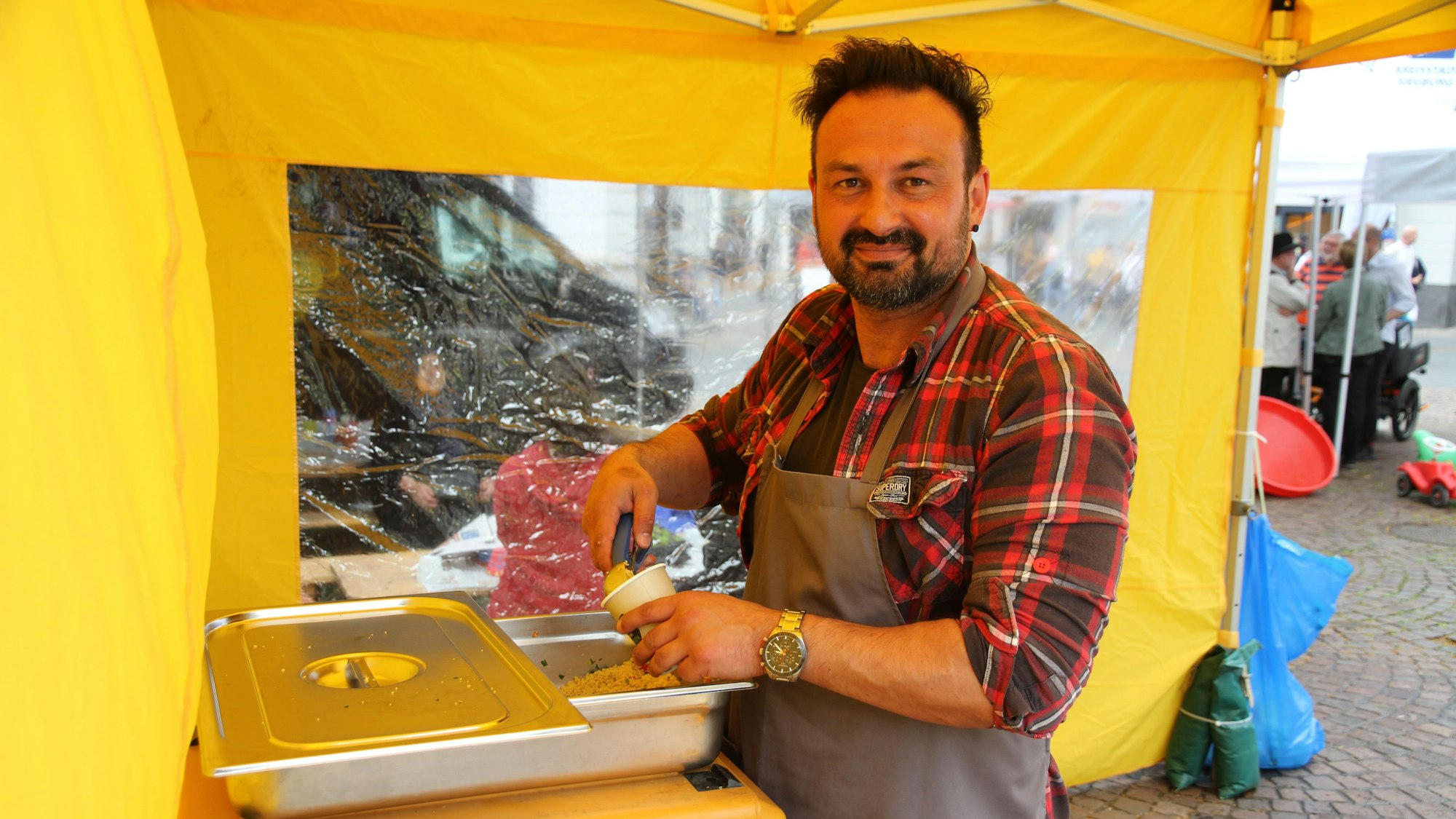 Ein Mann mit einer Kochschürze und Schüssel Couscous-Salat